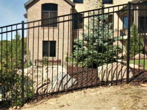 An ornamental metal fence made of steel that is sloping with the ground